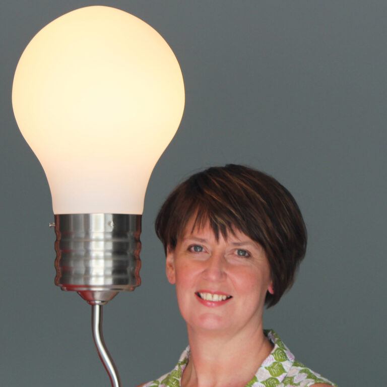 Woman smiling next to a giant lightbulb