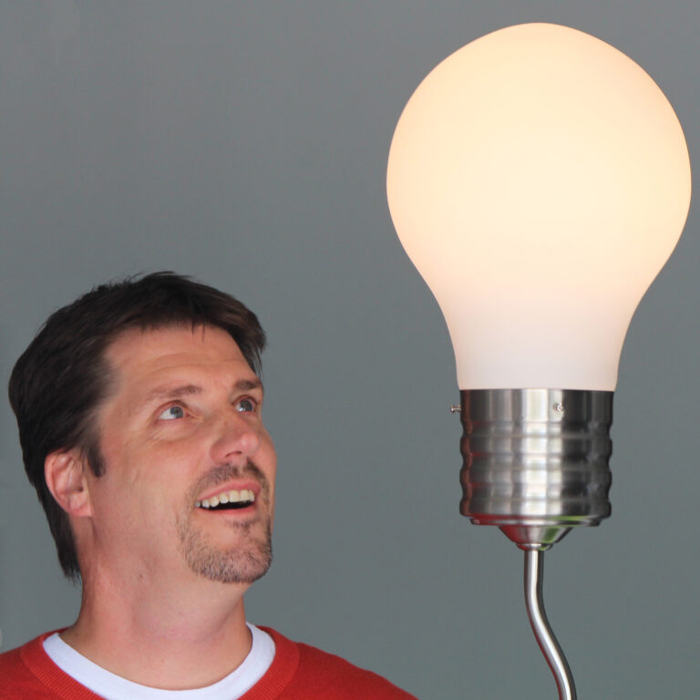 Man smiling and looking at a giant lightbulb